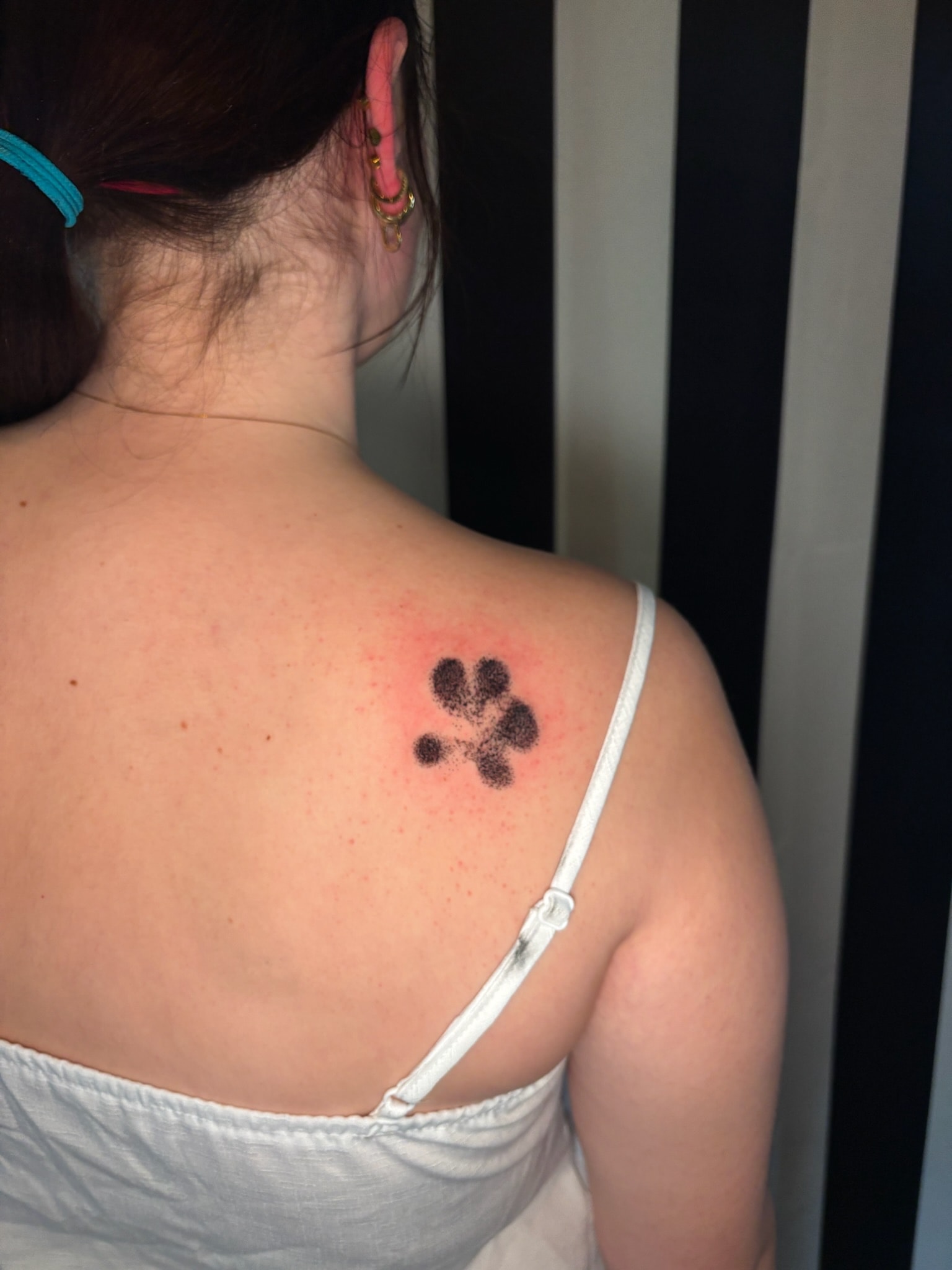 Paw print tattoo on shoulder blade, fine line