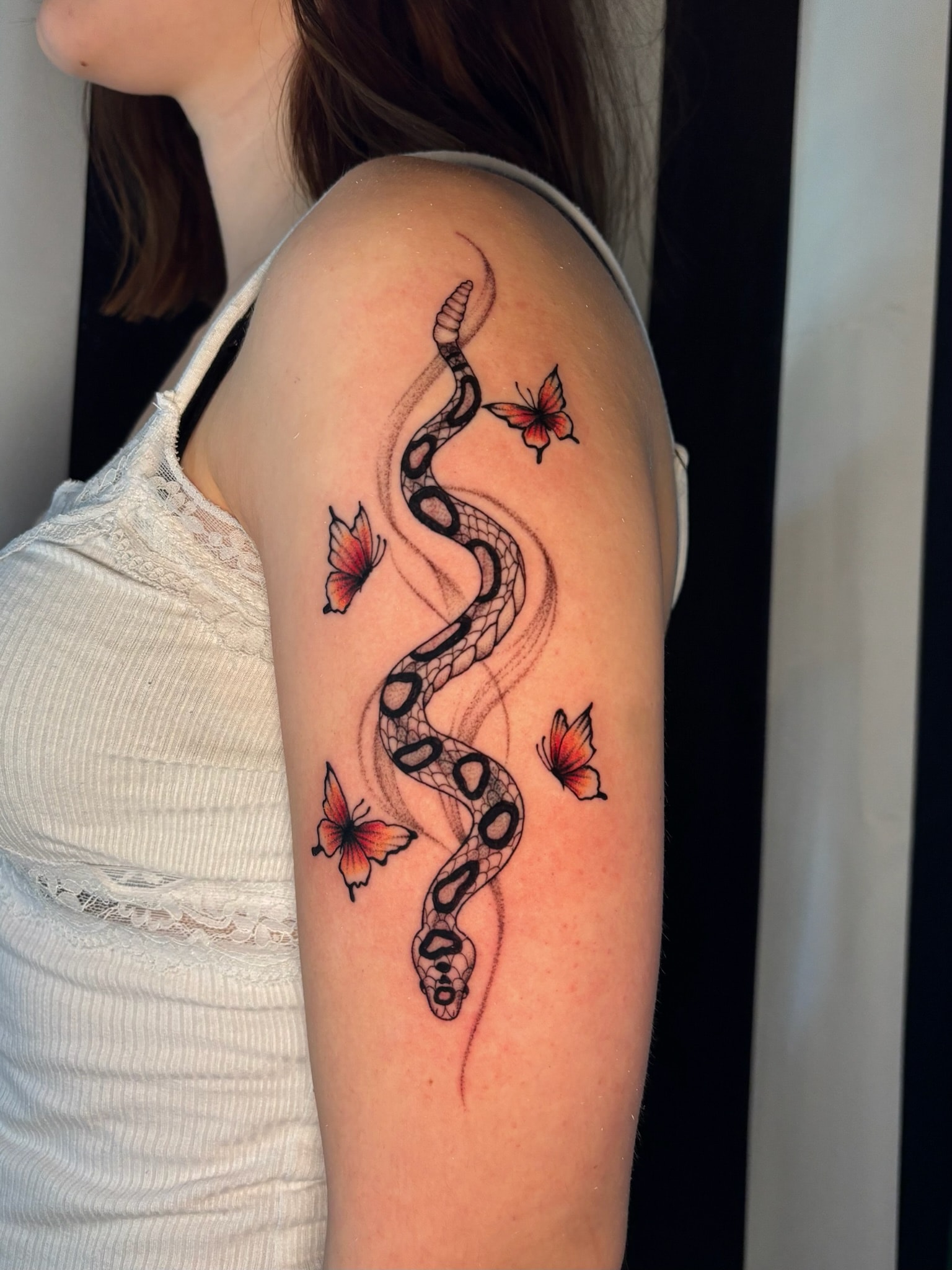 Snake and orange butterflies upper arm tattoo, neo-traditional color