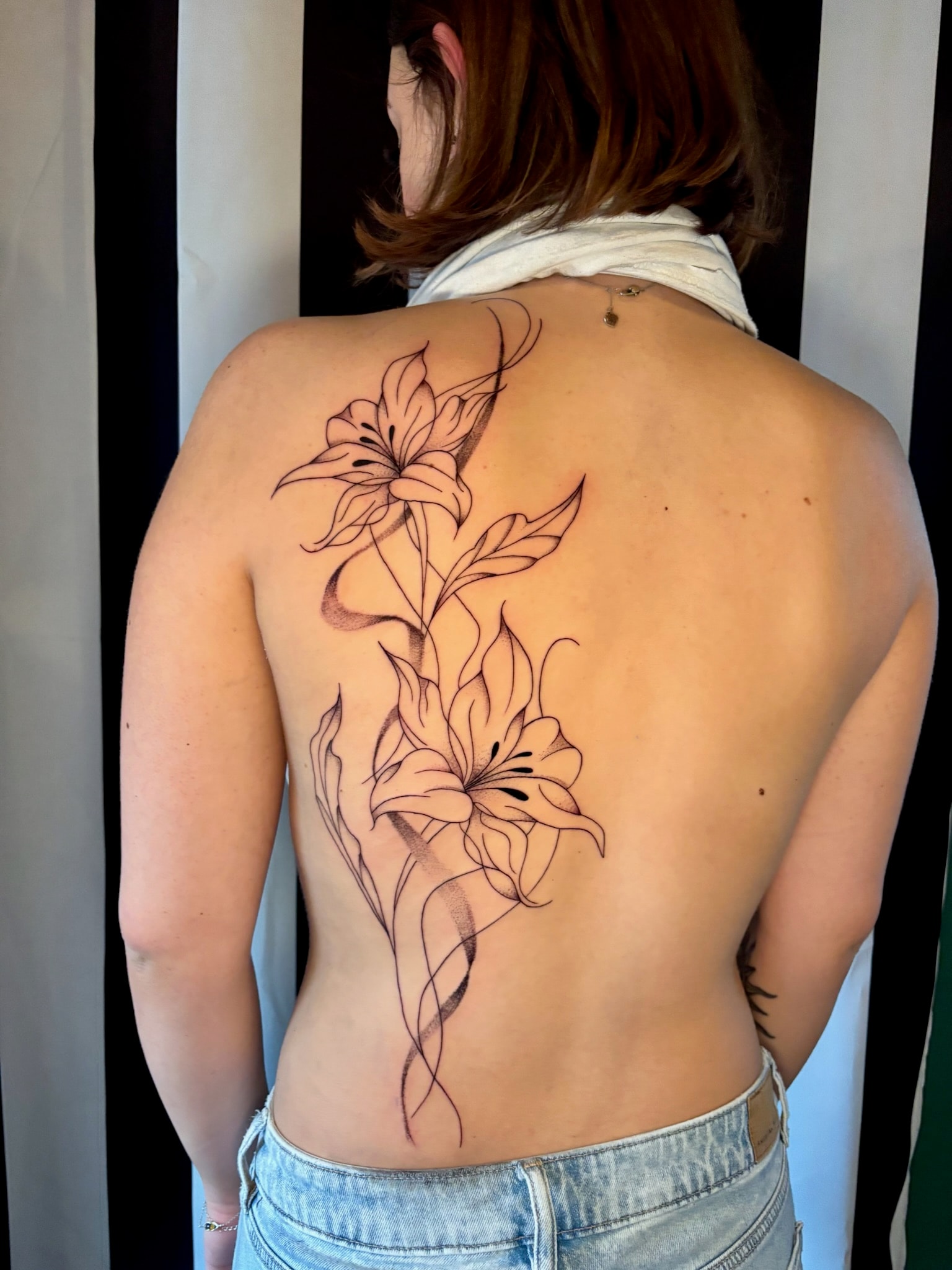 Woman with delicate floral spine tattoo, back view, fine line