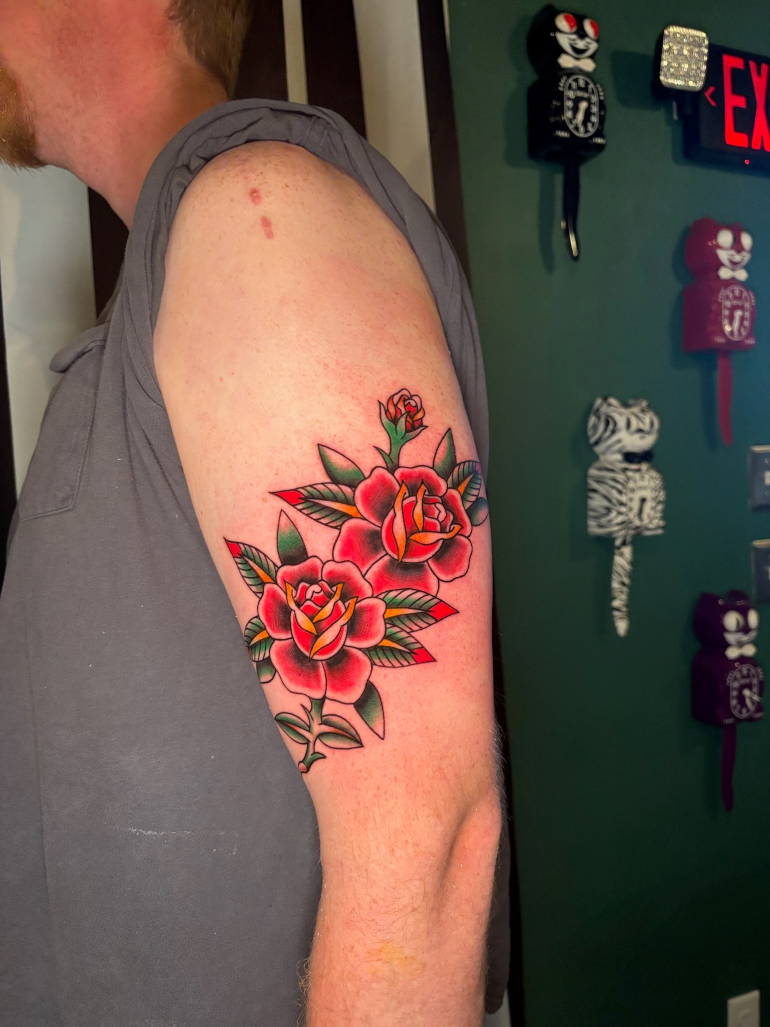 Bold red roses tattoo on arm and shoulder, traditional color