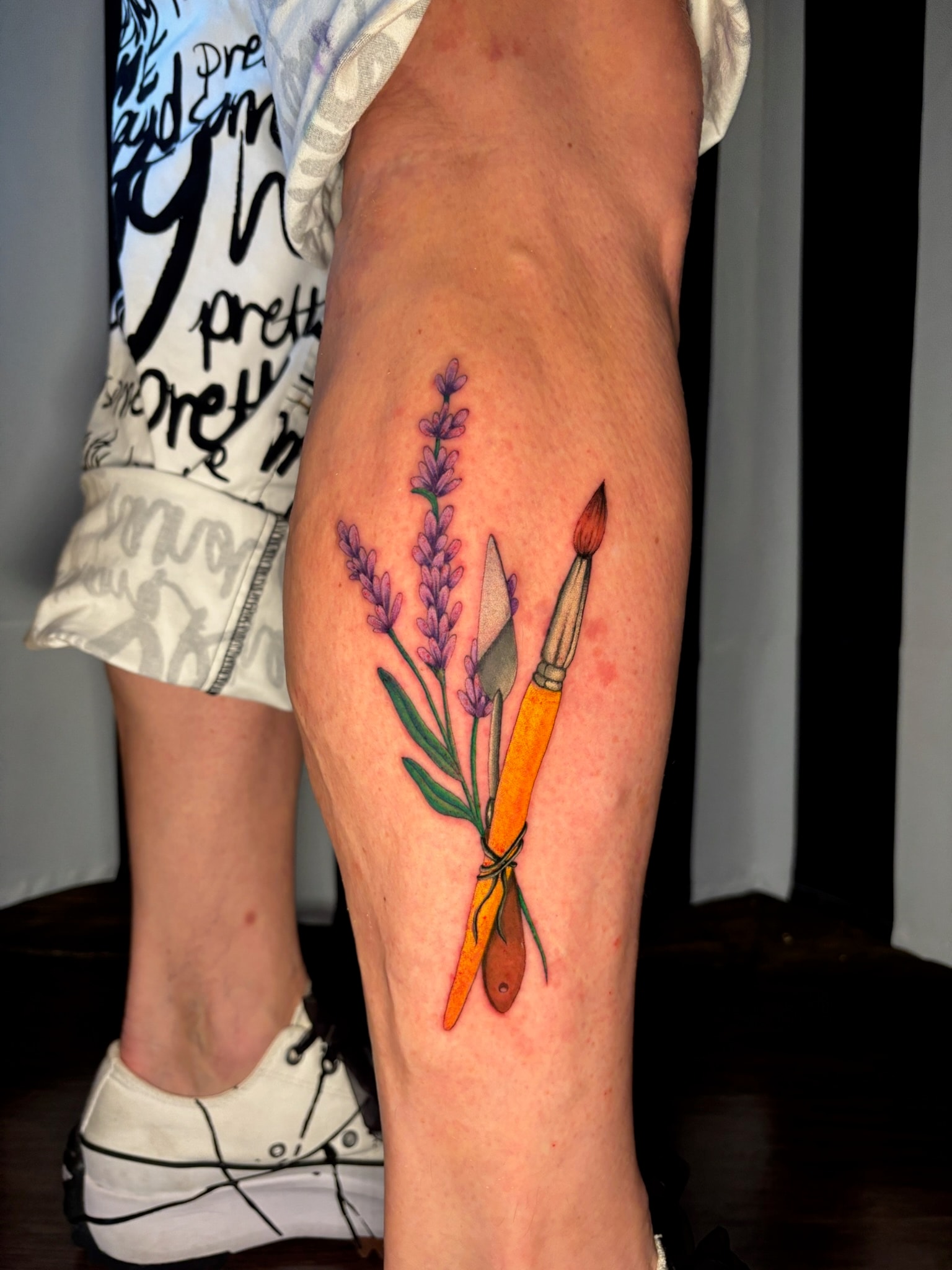 Lavender flowers with paintbrush tattoo on leg, fine line