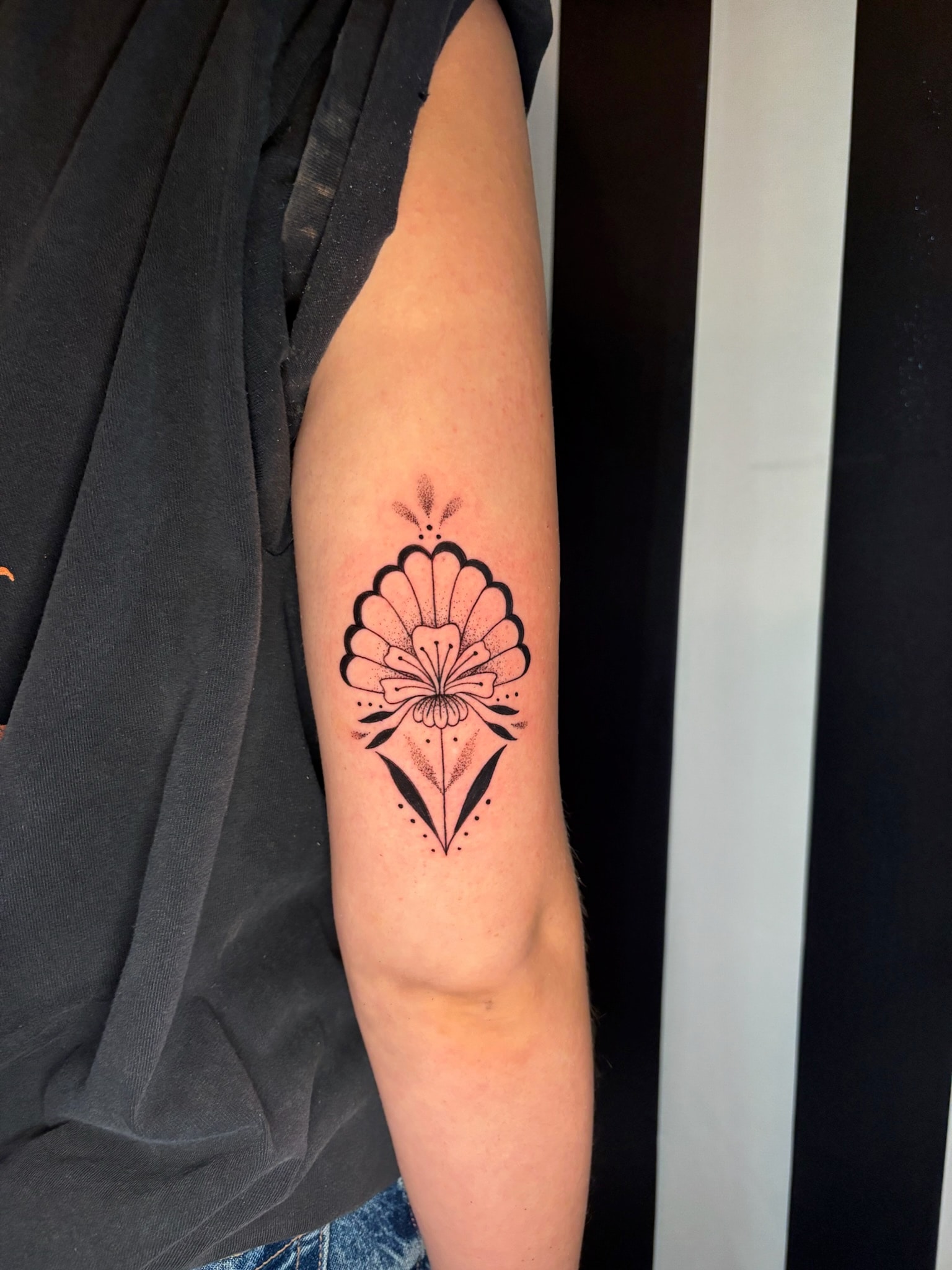 Decorative shell and flower tattoo on arm, neo-traditional