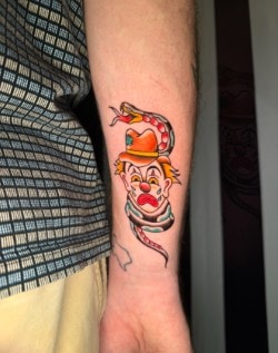 Colorful traditional clown face tattoo on arm