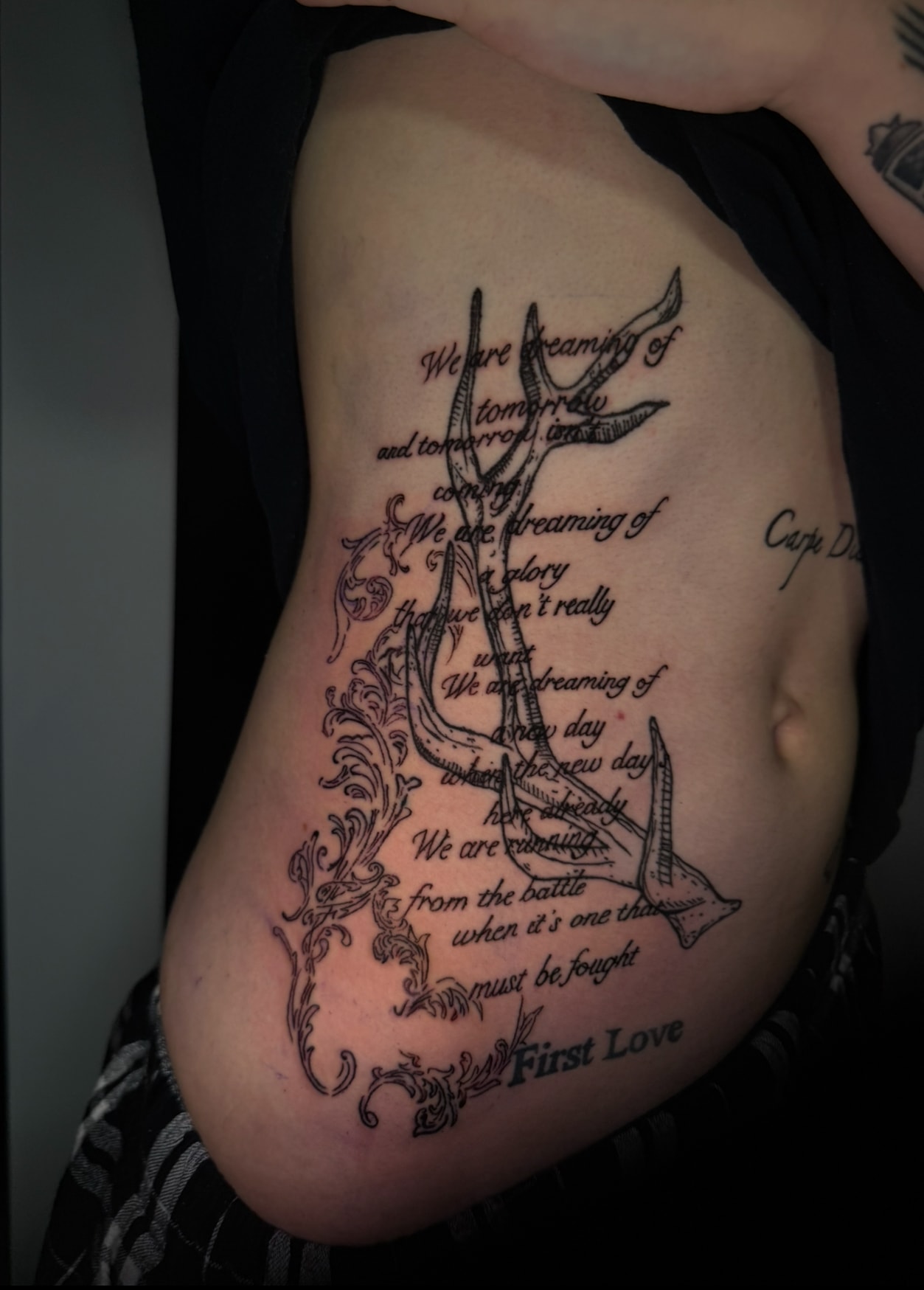 Text tattoo with decorative thorns on ribs, fine line